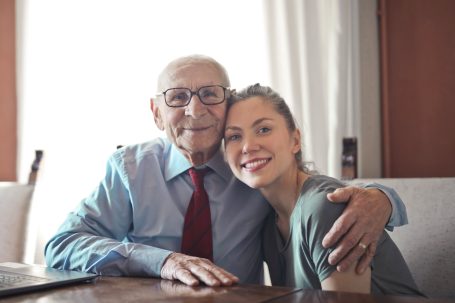 An elderly posing for picture with a young female carer